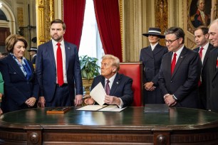 President Donald Trump at a signing ceremony post 60th Presidential Inauguration, surrounded by notable figures including Sen. Amy Klobuchar, Vice President JD Vance, First Lady Melania Trump, and central House members.