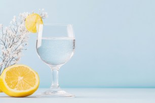 There are many benefits to substituting water for booze in January — and beyond. A glass of water, a sliced lemon and a floral decoration are pictured here.