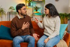 Upset young couple in casual clothes arguing fighting while sitting on sofa in living room at home. 