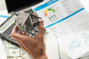 model home in a hand with papers in the background