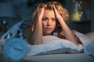 Desperate woman suffering from insomnia lies in bed awake at night