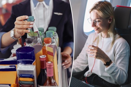 Stewardess in uniform removing a water bottle from a trolley cart in the cabin of a modern airplane