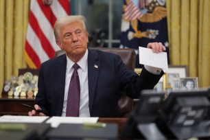 U.S. President Donald Trump holding a letter from former President Joe Biden in the Oval Office while signing executive orders on Inauguration Day, 2025.